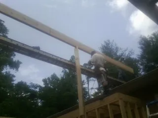 Carpenter setting a ridge beam over a new addition frame — Ice Dam Removal by Roofing Brothers in Aldrich