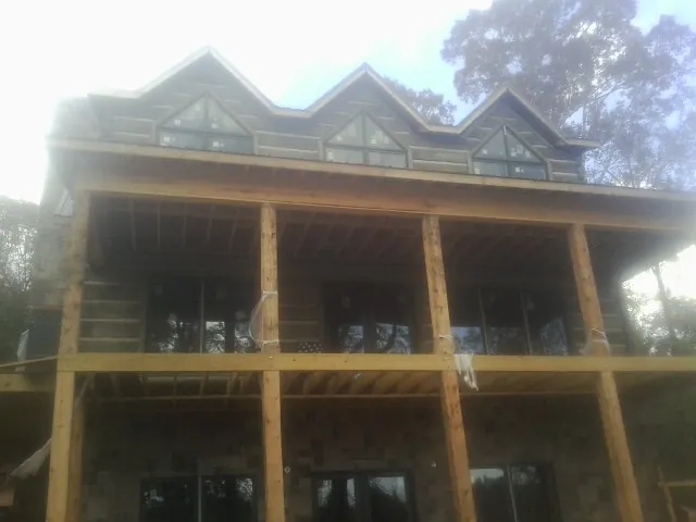 Dormers and porch framing on a large log home under construction — Roof Coating work by our crew in Aldrich