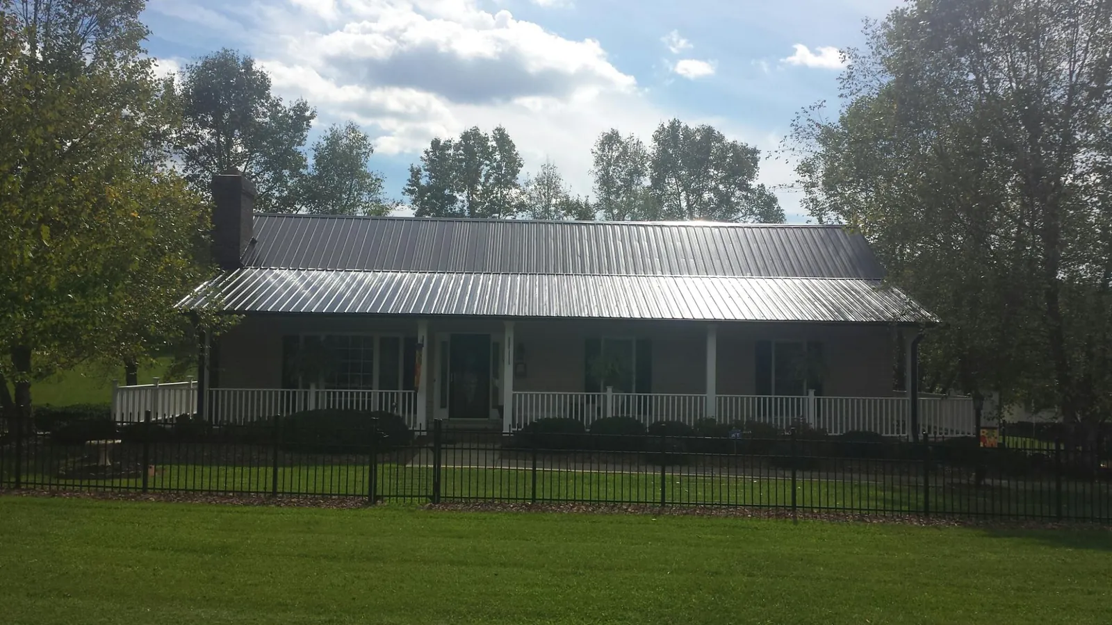 Gray metal roof on a brick ranch with a full width front porch — Gutter Guard Installation work by our crew in Aldrich
