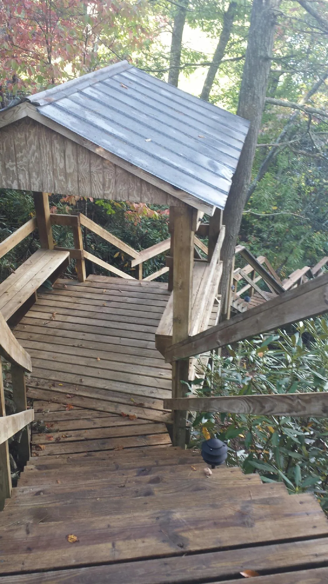 Metal roofed shelter over wooden steps on a wooded walkway — Skylight Repair & Installation work by our crew in Aldrich