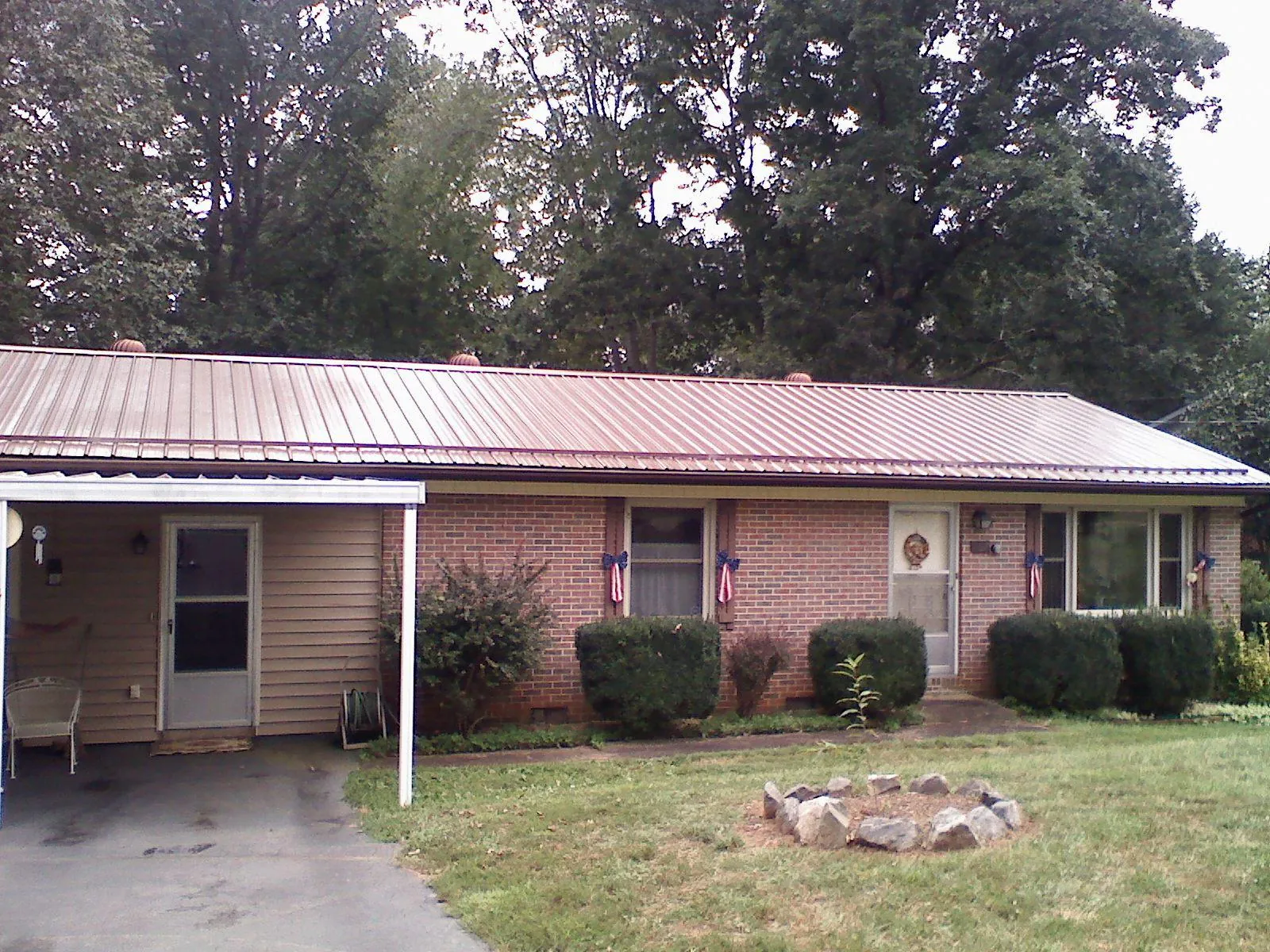 Bronze metal roof and carport on a brick ranch home — Roof Repair work by our crew in Aldrich