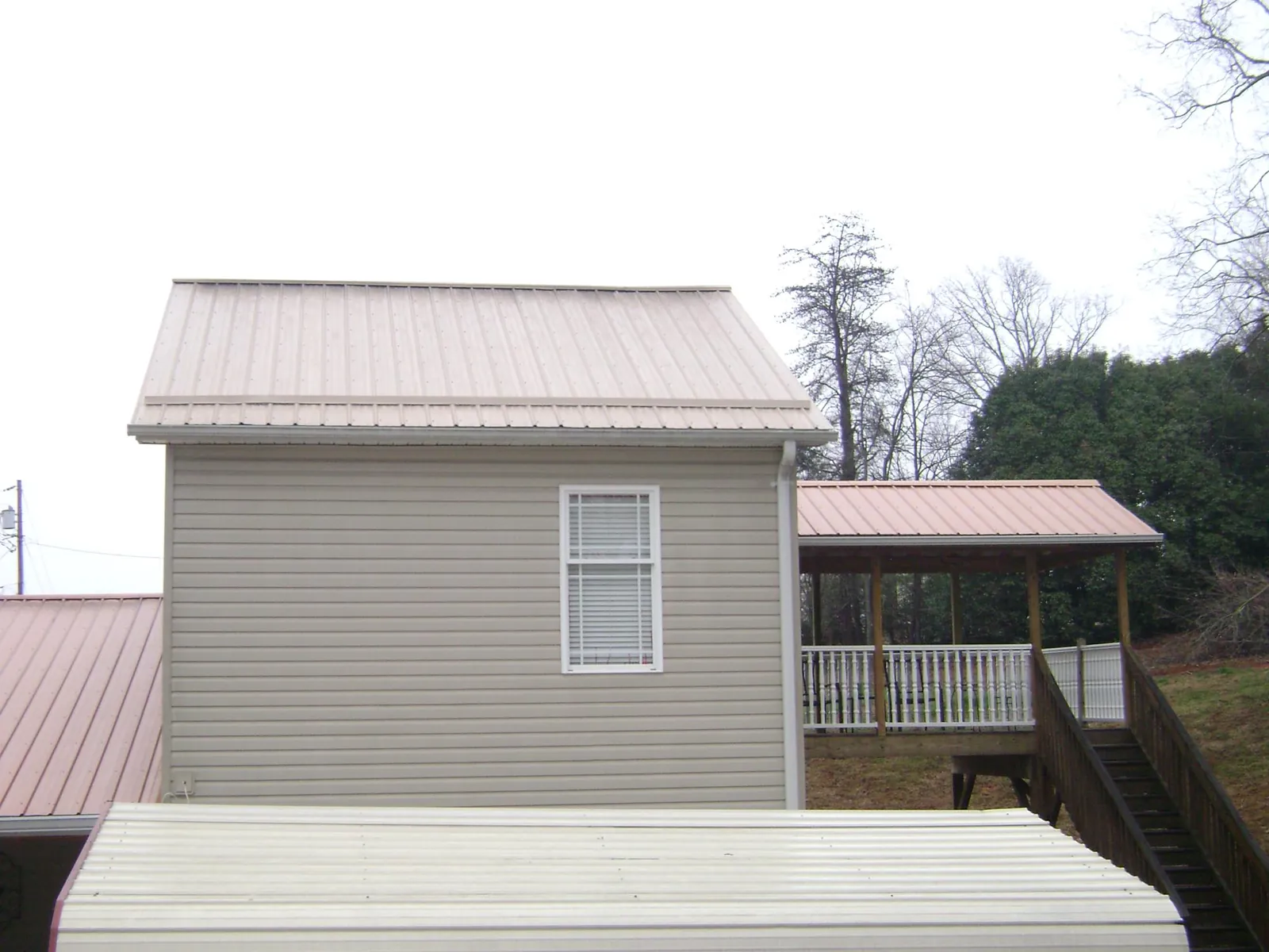 Tan metal roofs on a two story addition and attached porch, from a Roof Replacement job in Aldrich