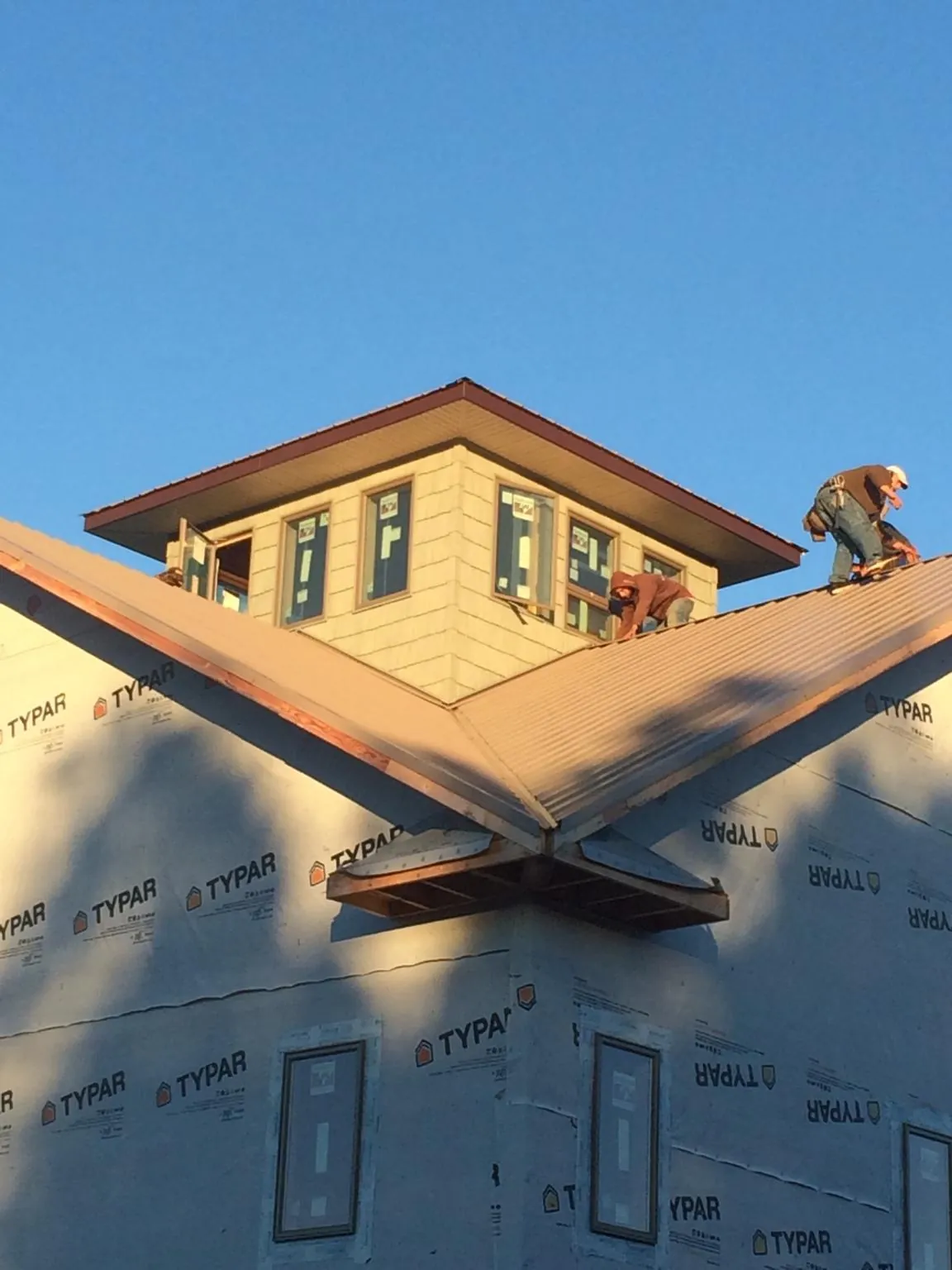 Roofers working around a rooftop cupola on a new metal roof at sunset — Roof Waterproofing in Aldrich by Roofing Brothers